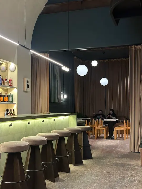 Minimalist green bar and cushioned stools inside Soft Bar + Cafe, an alcohol-free bar in Brooklyn